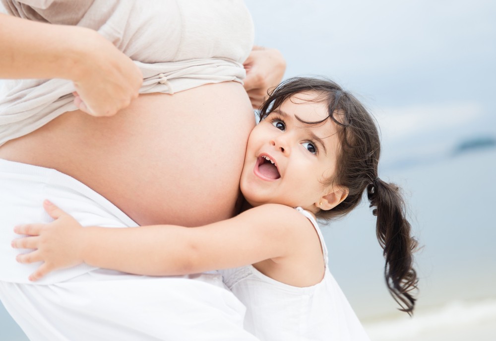 Toddler hugging baby belly mom