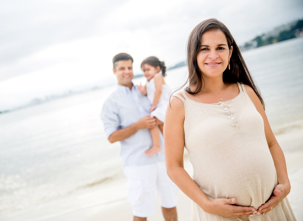 Pregnant mother standing in front of dad with older sibling