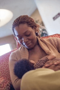 Woman sitting, looking at her baby nursing