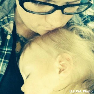 infant sleeping with head on parent's chest and parent's chin resting on top of infant's head 