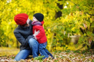 Mother and toddler playing in fall leaves