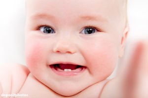 Closeup of baby smiling, her bottom two teeth showing 