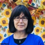 Yocheved standing in front of a wall with painted sunflowers