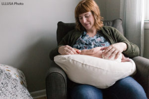 Rebecca sitting, watching her baby sleep on her lap