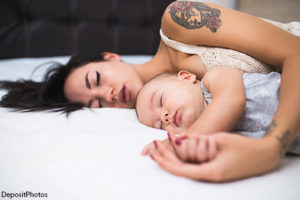 Mother napping with her baby, in a save sleep situation