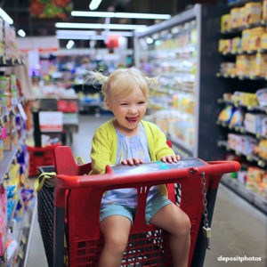 toddler sitting in shopping cart laughing 