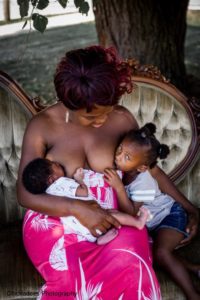 Darke County Live Love Latch Event, Mother sitting on couch tandemfeeding her toddler an baby