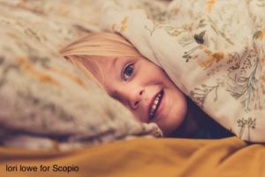 Toddler smiling between bedding