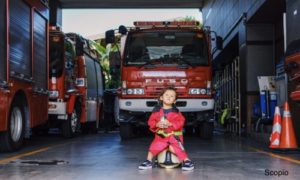 Toddler sitting against fire truck