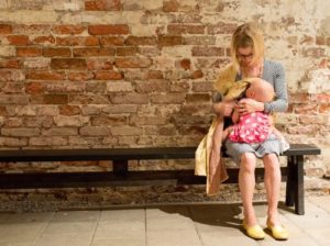 Mother sitting trying to nurse her baby